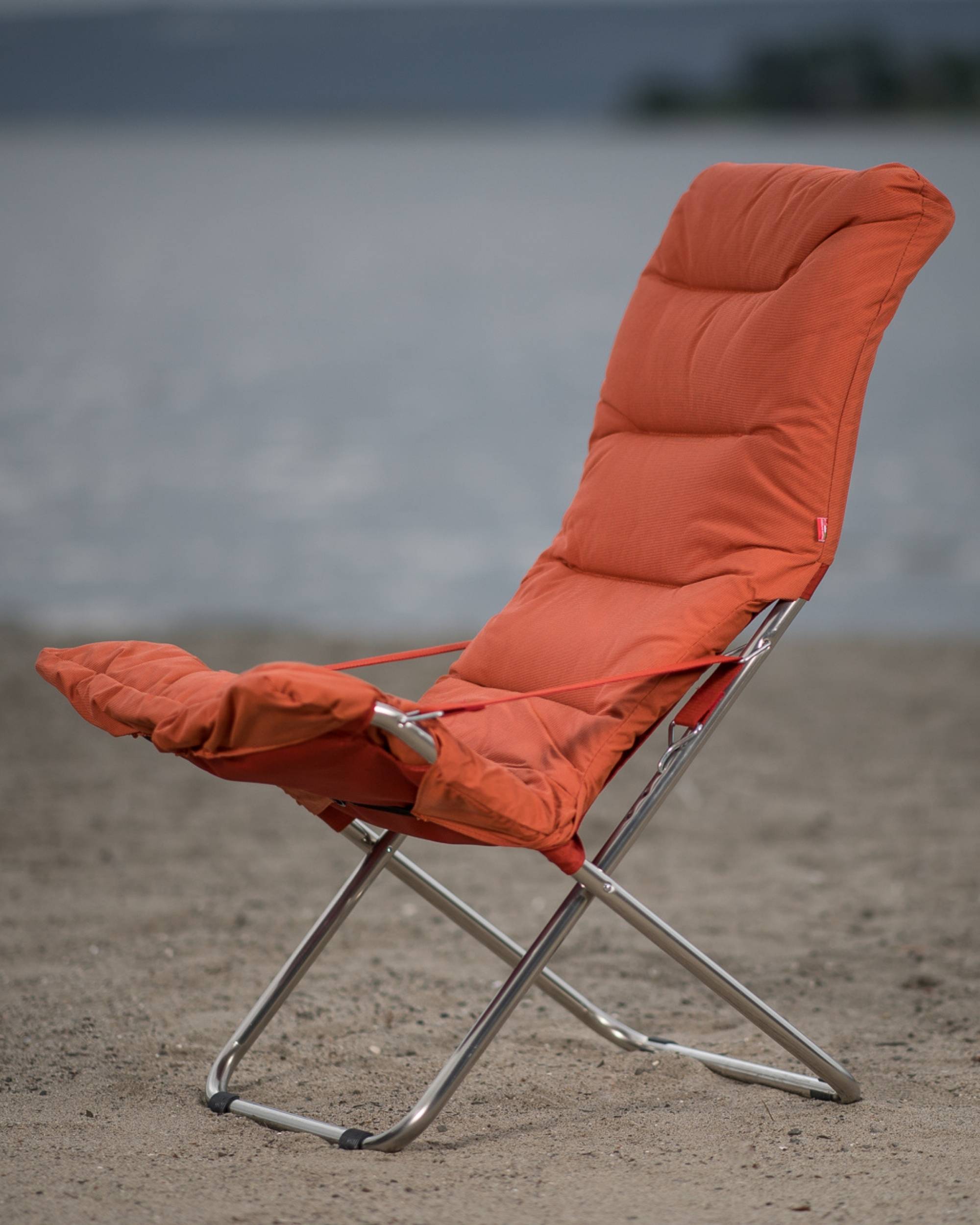 Fiam Fiesta Soft solstol med pute i fargen orange pÄ en strand