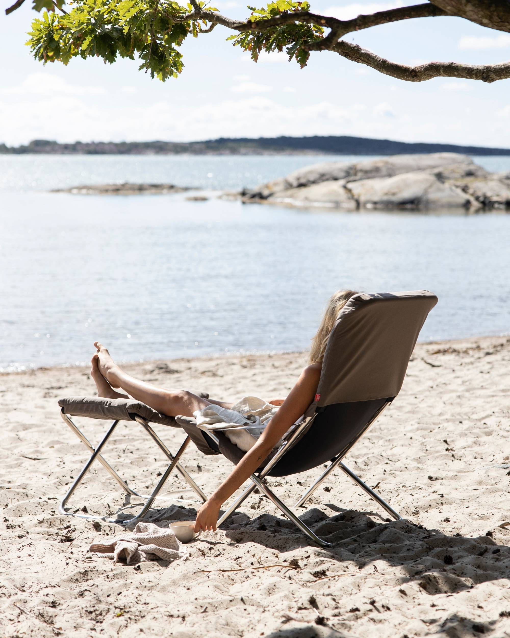 Fiam Fiesta soft solstol og fotskammel med pute i fargen brun pÄ stranden