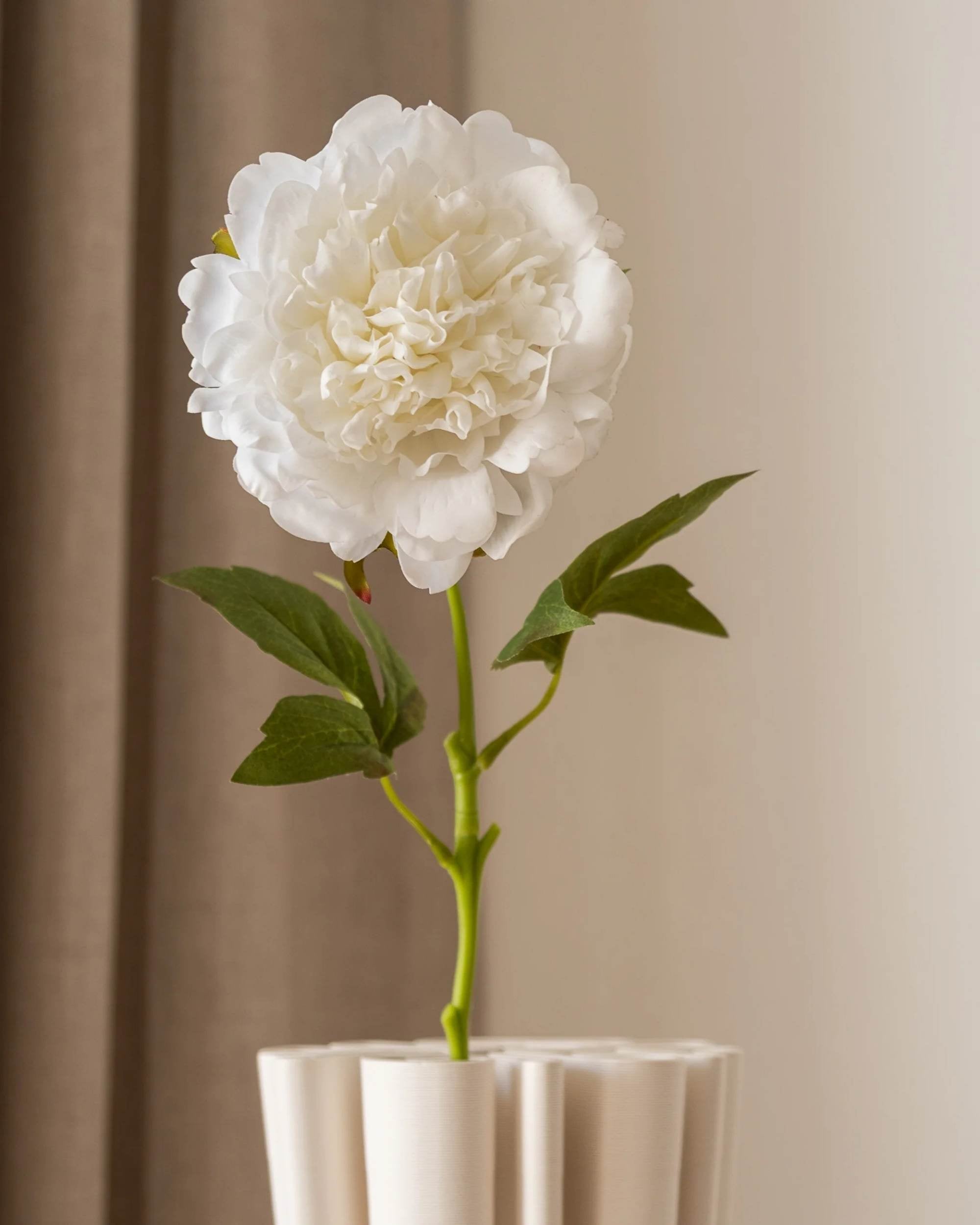 Amarante Peon i helfigur, hvit og elegant kunstig blomst med grÞnne blader, stÄr i en lys vase.
