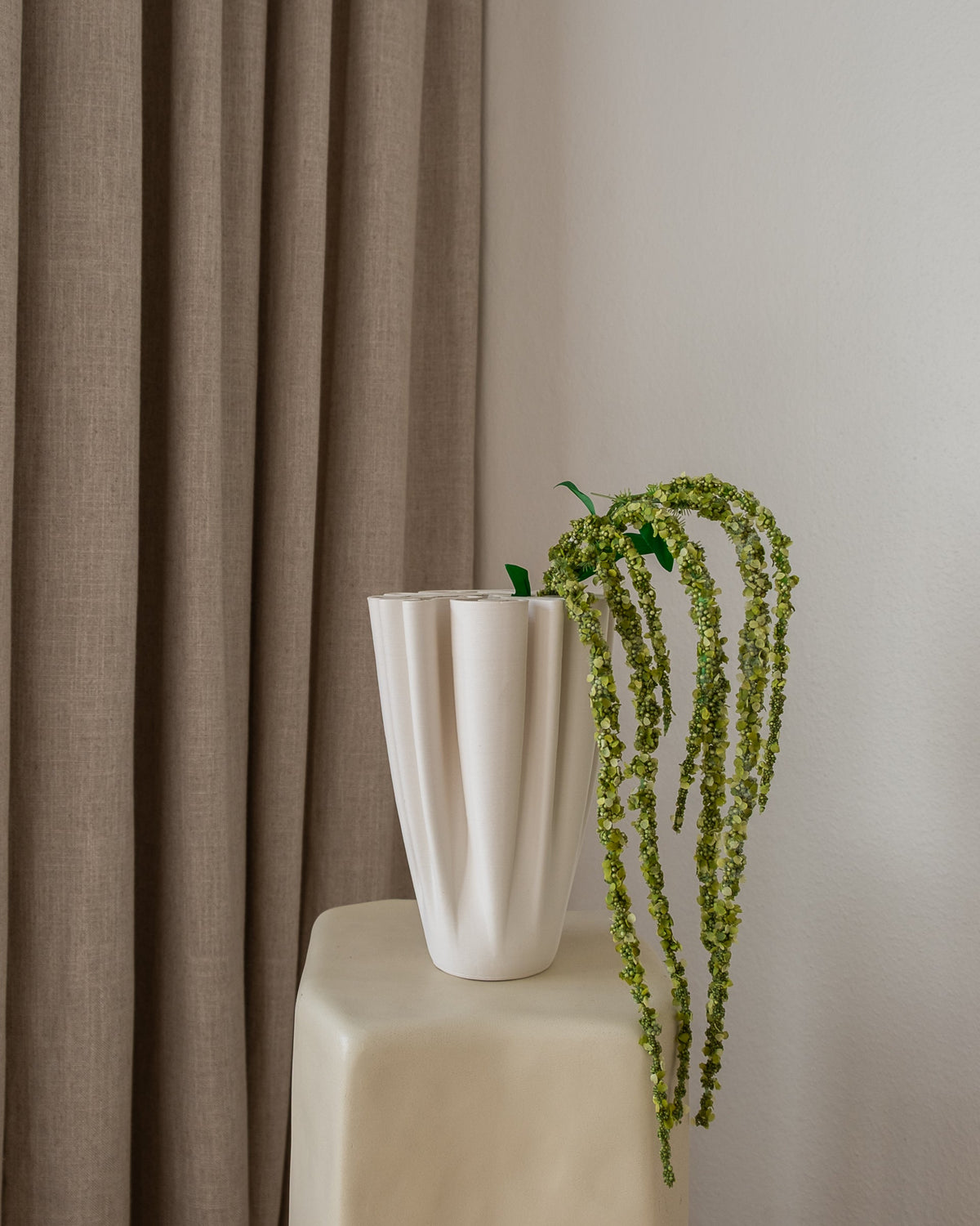 Detalj av Amaranthus kunstig blomst fra Amarante med livlige grønne kaskader fra hvit rillet vase