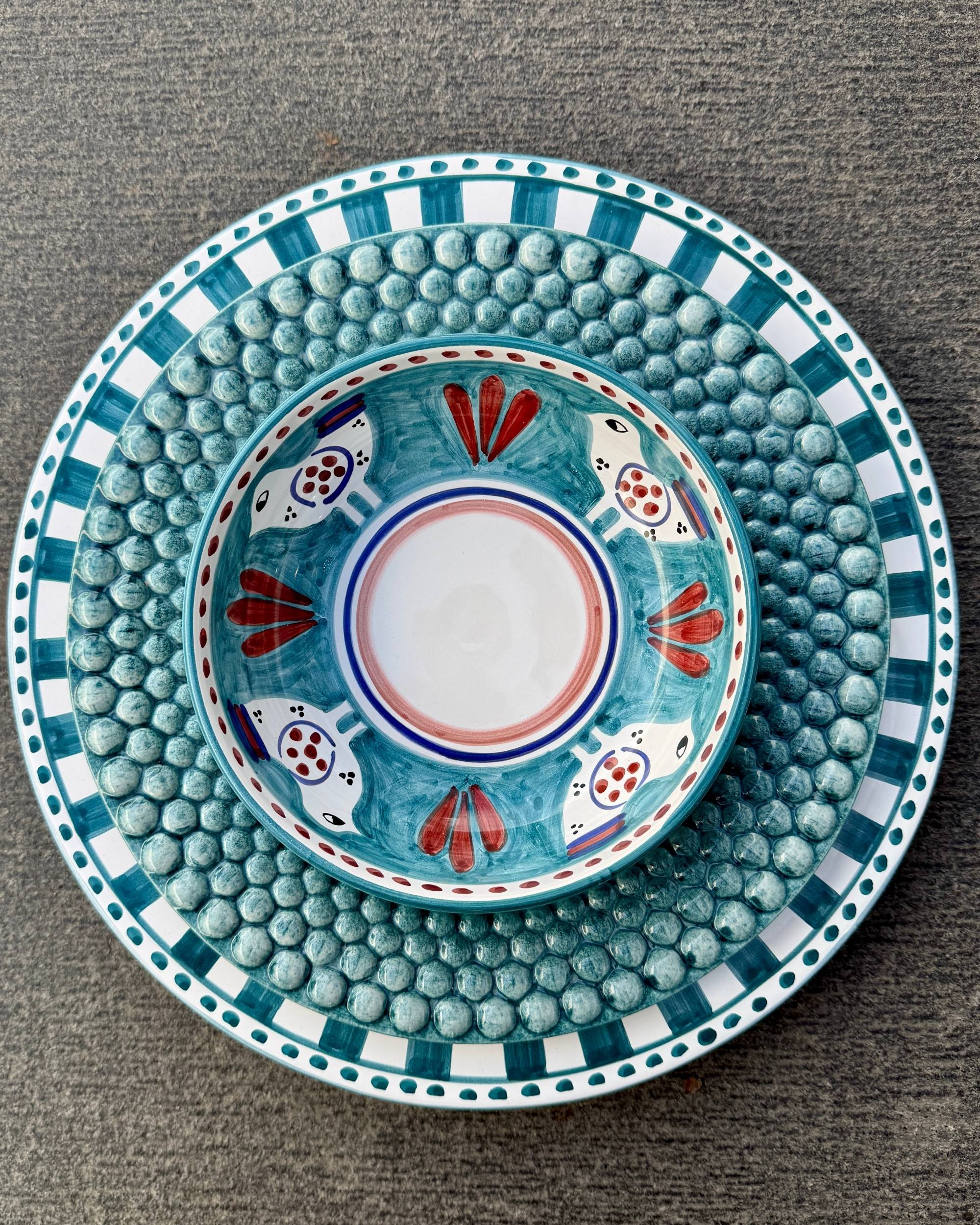 Amalfi Bolle fra Dipinto Ceramics stablet, viser håndmalt dekordesign av fugler og røde bladmotiver.