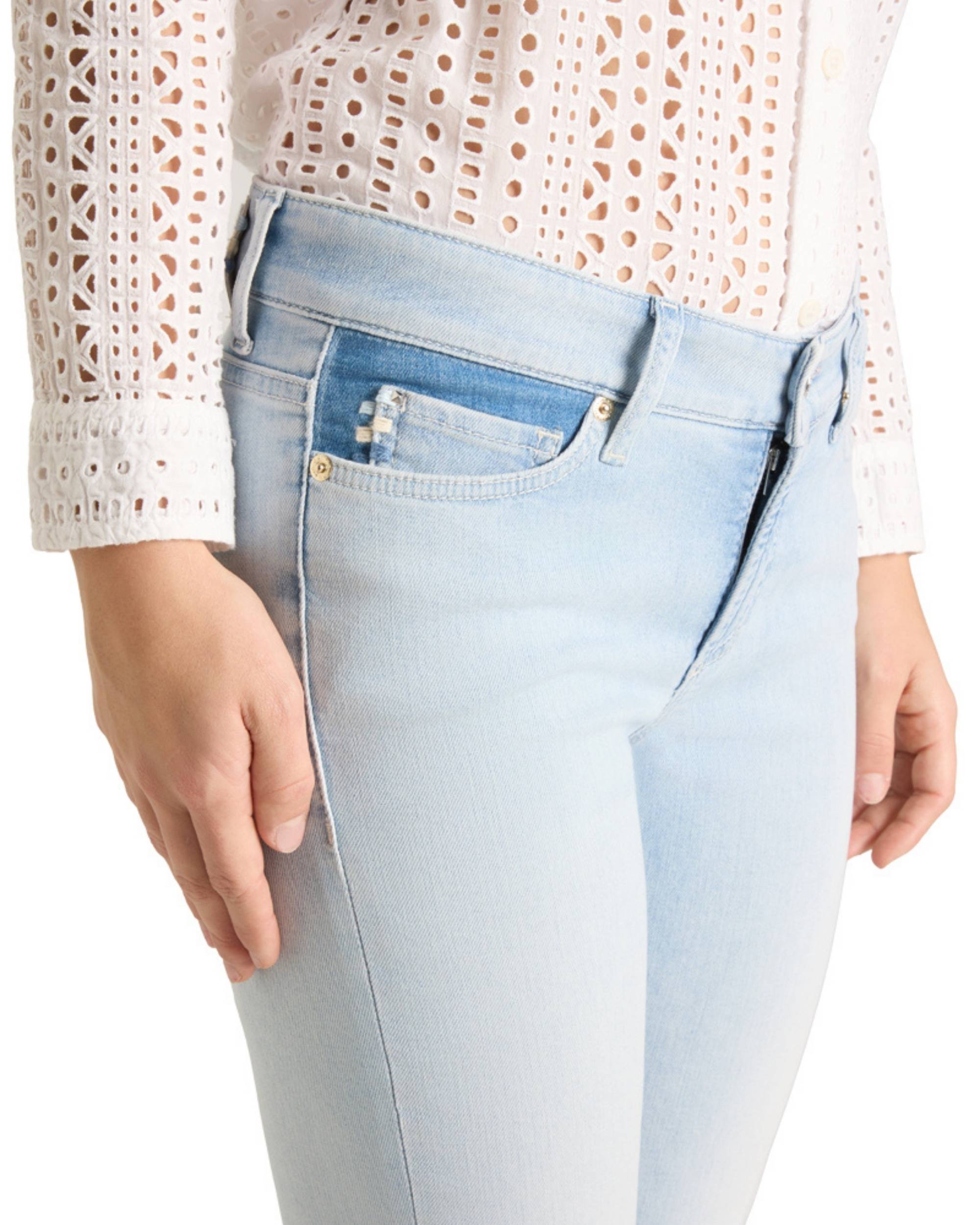 Cambio Piper Cropped Fringed bukse i lyseblå denim, detalj av frontlomme og lukning med glidelås og knapp.