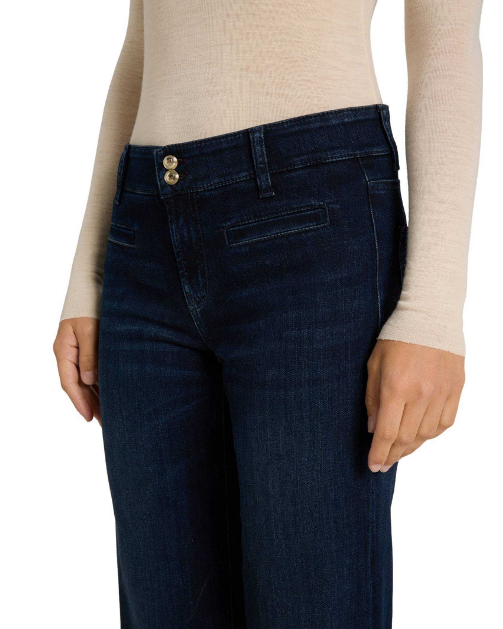 Cambio Tessa bukse i mørkeblå denim. Nærbilde av linningen med to gylne knapper og en horisontal lommedetalj.